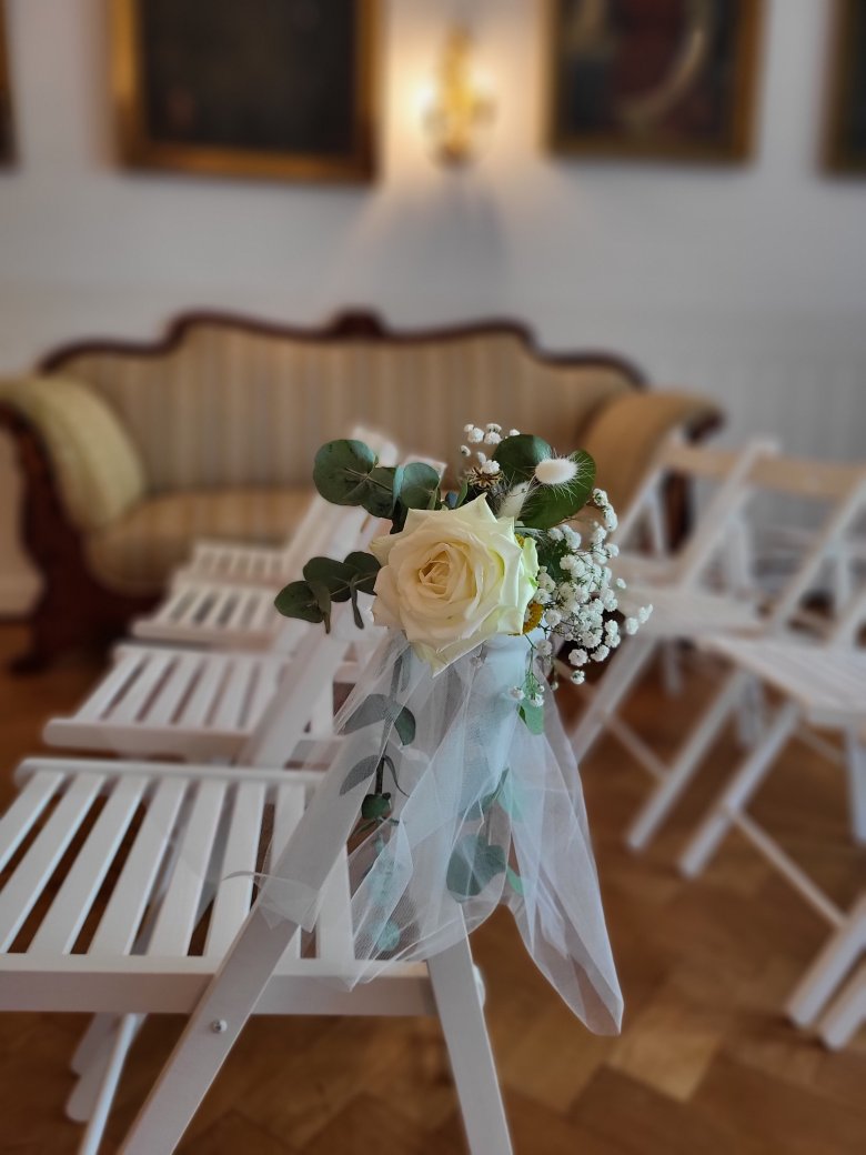 weißer Stuhl mit Blumendeko im Hintergrund ist ein Sofa zu sehen